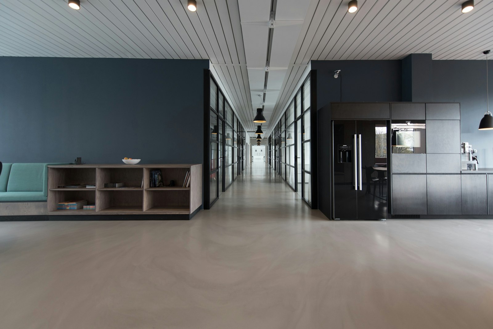 Quiet modern software studio with empty desks, monitors, and natural light through glass walls